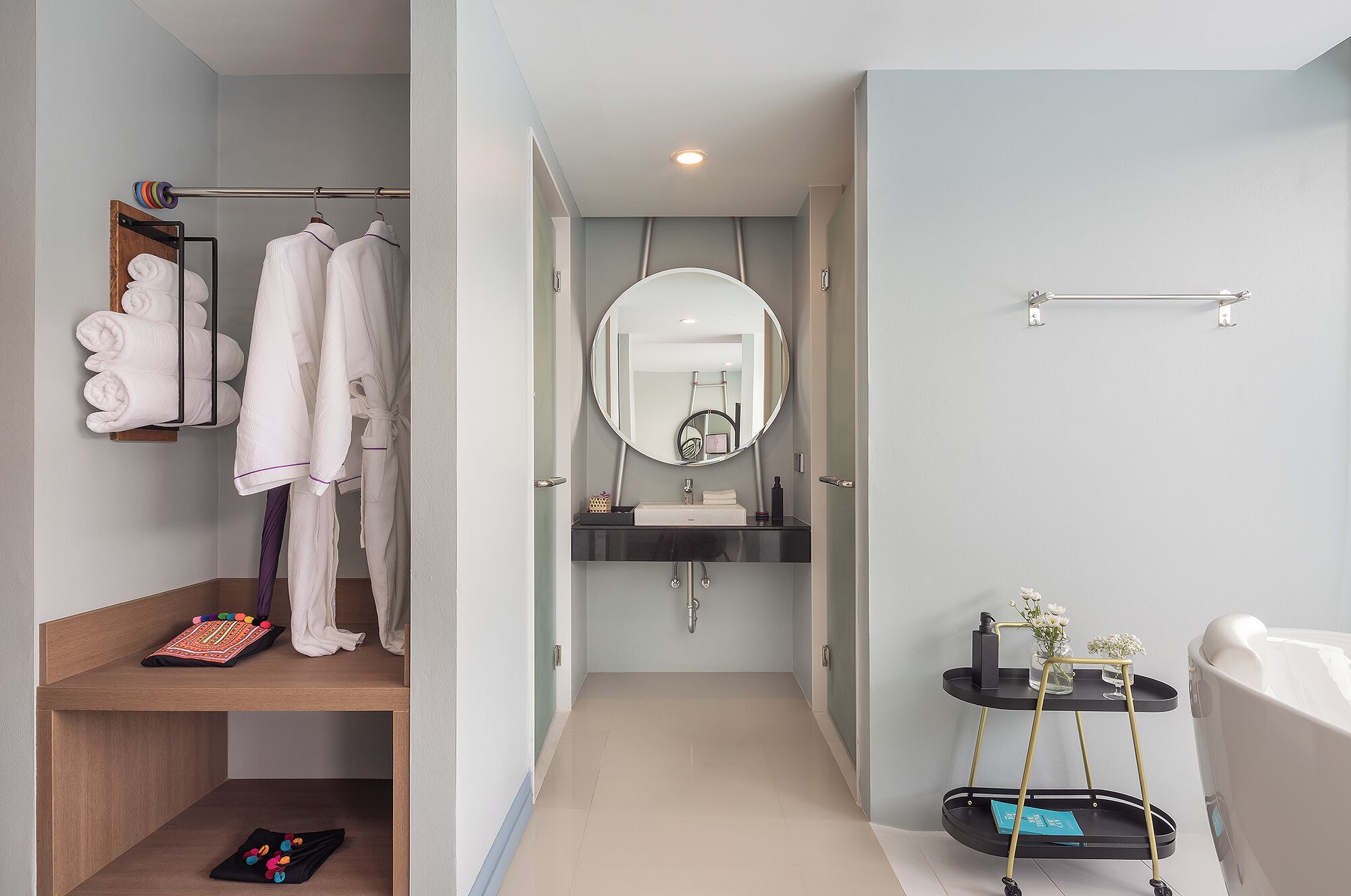 A modern bathroom with a vanity, mirror, towel rack, and a small shelf with toiletries.