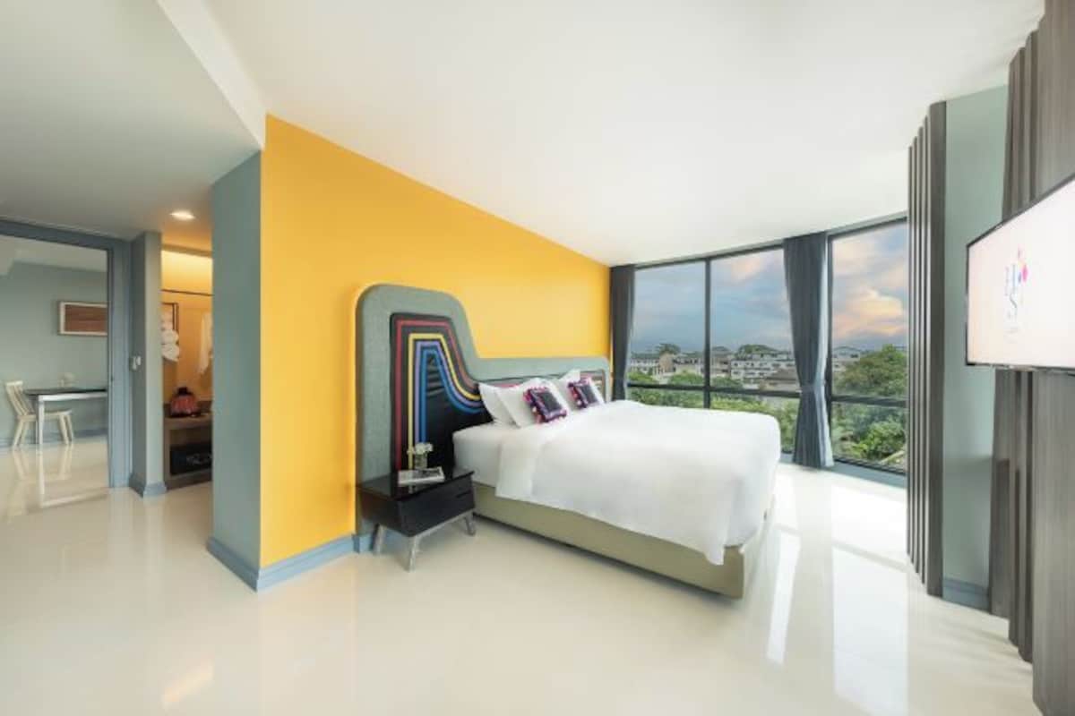 Un dormitorio moderno con una cama grande, una mesita de noche, un escritorio y vistas a la ciudad.