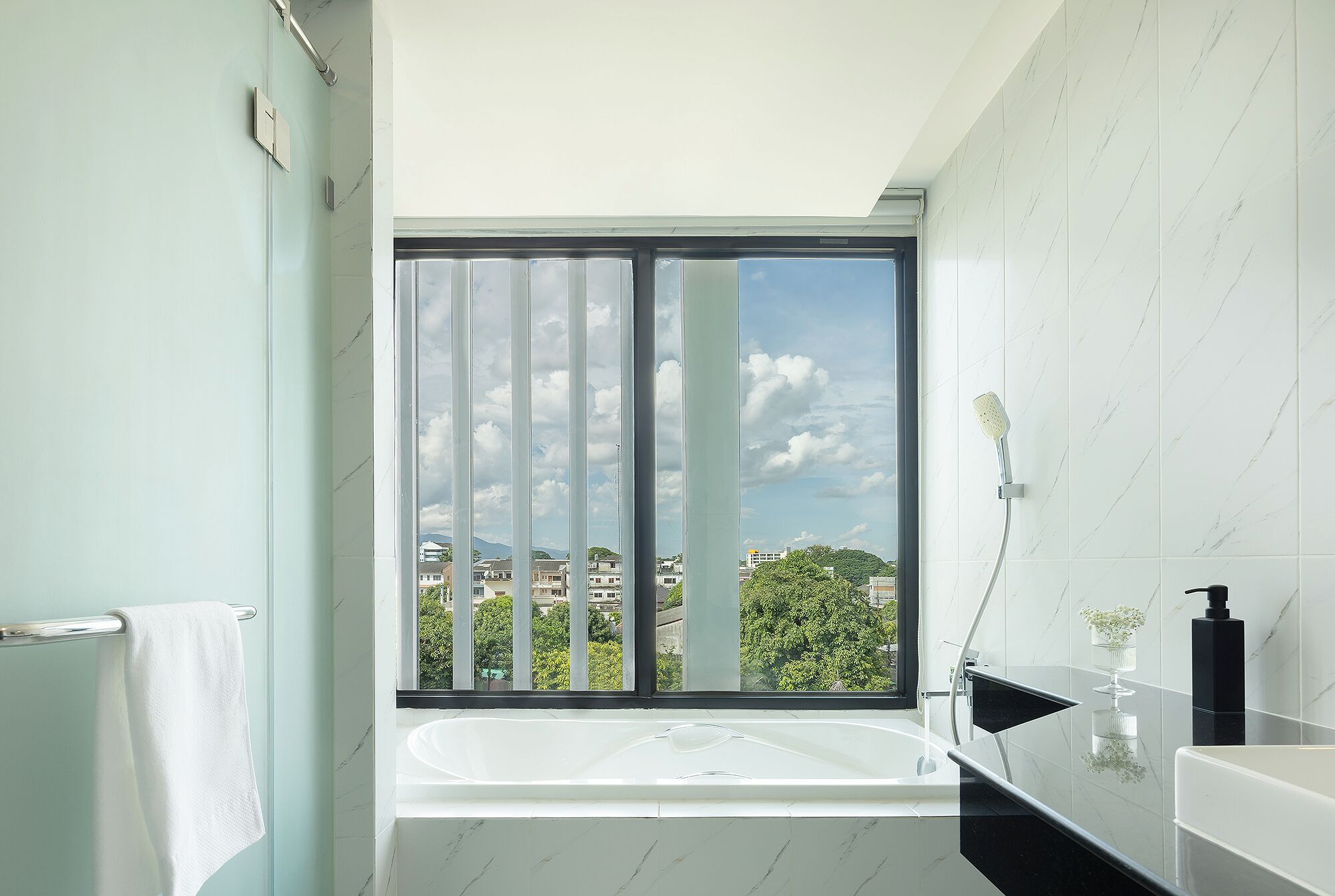 A modern bathroom with a large window, a bathtub, and a shower.
