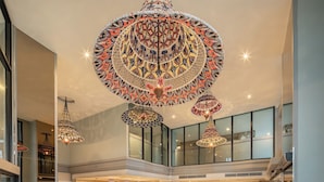 A spacious lobby with a high ceiling, multiple hanging lamps, a reception desk, seating areas, and large windows. - Hotel Selene Chiang Rai (Chiang Rai)