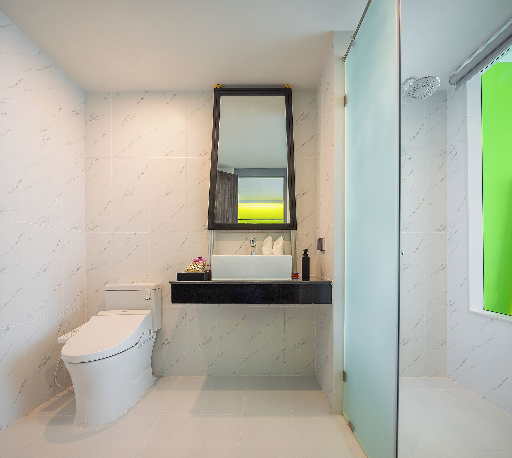 Een moderne badkamer met een wit toilet, een zwart wastafelmeubel en een spiegel erboven.