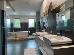 A modern bathroom with a freestanding bathtub, a large mirror, and a glass-enclosed shower area. - The Palm - Beachside Home with Heated Pool, Cinema & Games Room (Mudjimba)