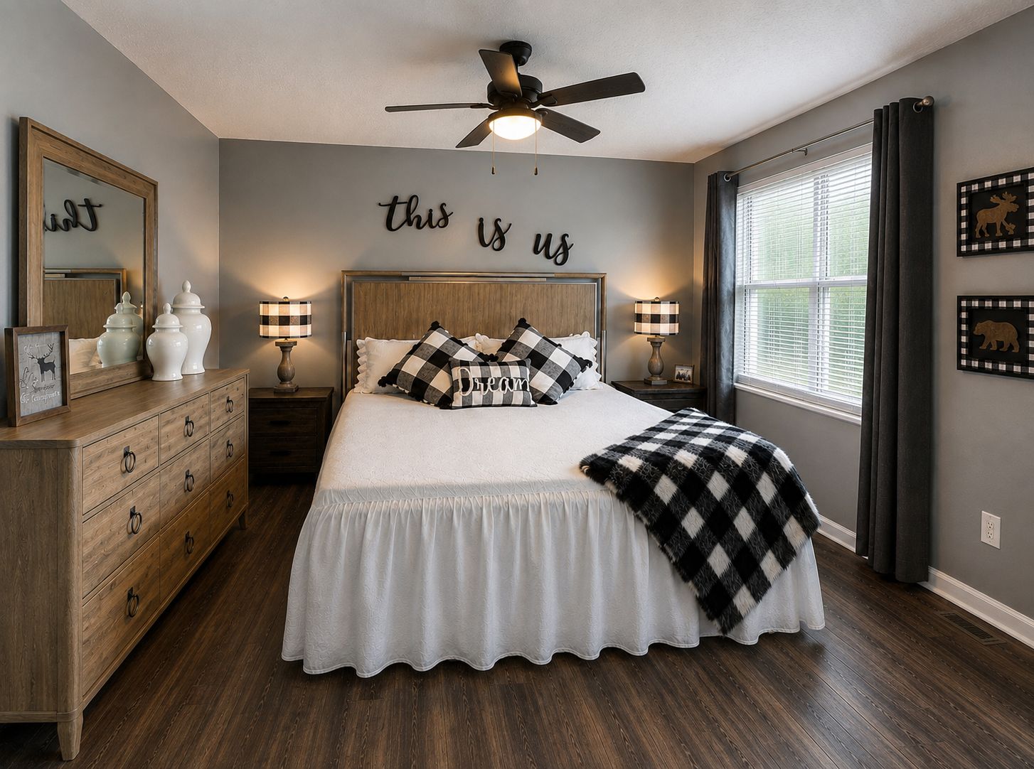 A bedroom with a bed, dresser, nightstands, lamps, a ceiling fan, a window with curtains, and wall decor.