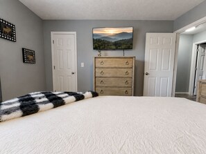 A bedroom with a bed, a dresser, a television, and two doors. - Amazing Beds!-2 miles to Dollywood-The Island-Tanger (Sevierville)
