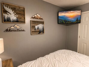 A bedroom with a bed, a TV mounted on the wall, and three framed wall decorations. - Amazing Beds!-2 miles to Dollywood-The Island-Tanger (Sevierville)
