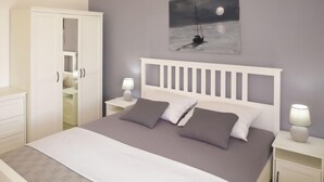 Een slaapkamer met een bed, nachtkastjes, een kledingkast en een schilderij van een zeilboot aan de muur.