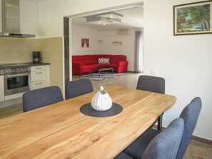 Uma cozinha moderna com forno embutido e área de refeições com mesa de madeira e quatro cadeiras.
