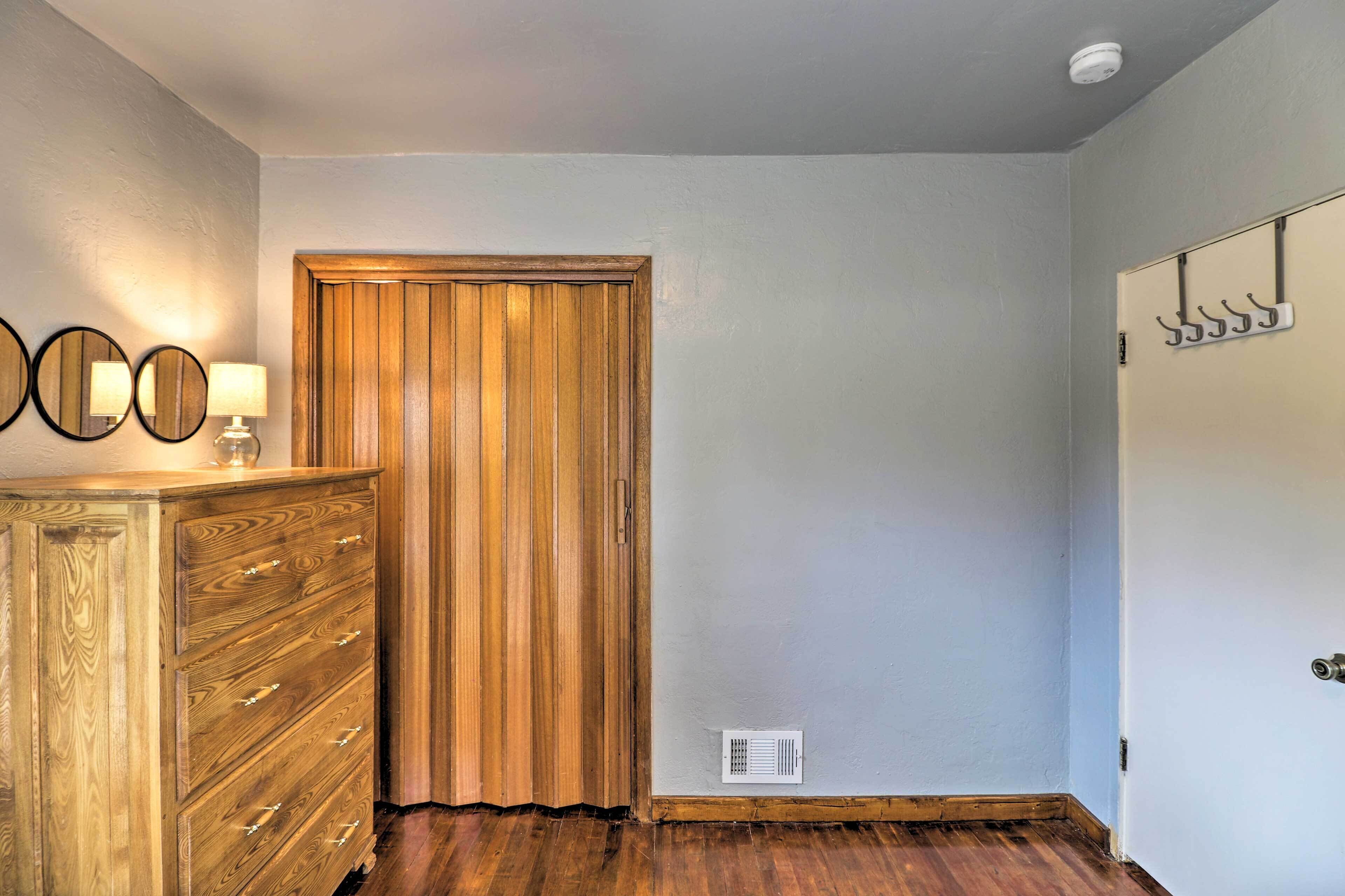 A room with a wooden dresser, a mirror, and a door with a coat rack.