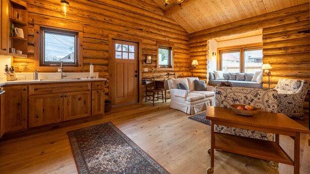 Interior de una cabaña de madera con cocina, comedor y zona de estar.