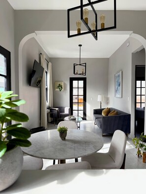 Una sala de estar moderna con una mesa redonda de mármol, un sofá oscuro y una lámpara con un diseño geométrico original.