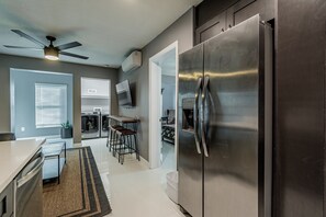 A modern kitchen with a stainless steel refrigerator, a ceiling fan, and a dining area with bar stools.