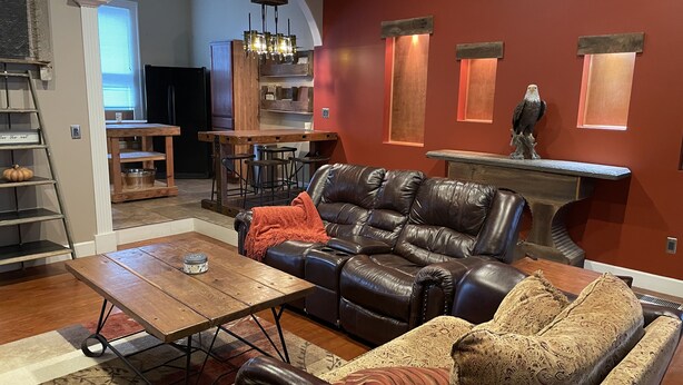 Ein Wohnzimmer mit einer Ledersofa, einem Holztisch und einem gemusterten Teppich.