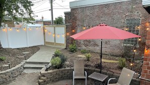Eine Terrasse mit Ziegelwand, Sitzgelegenheiten im Freien und Lichterketten.