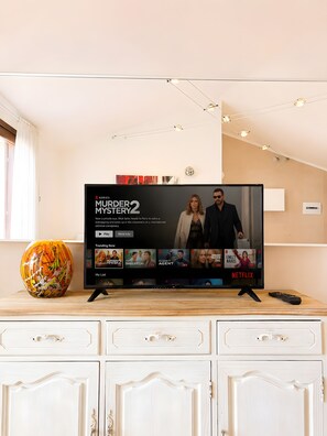 En tv-skärm som visar filmen ”Murder Mystery 2” på Netflix. På tv-bänken står en vas och en fjärrkontroll.