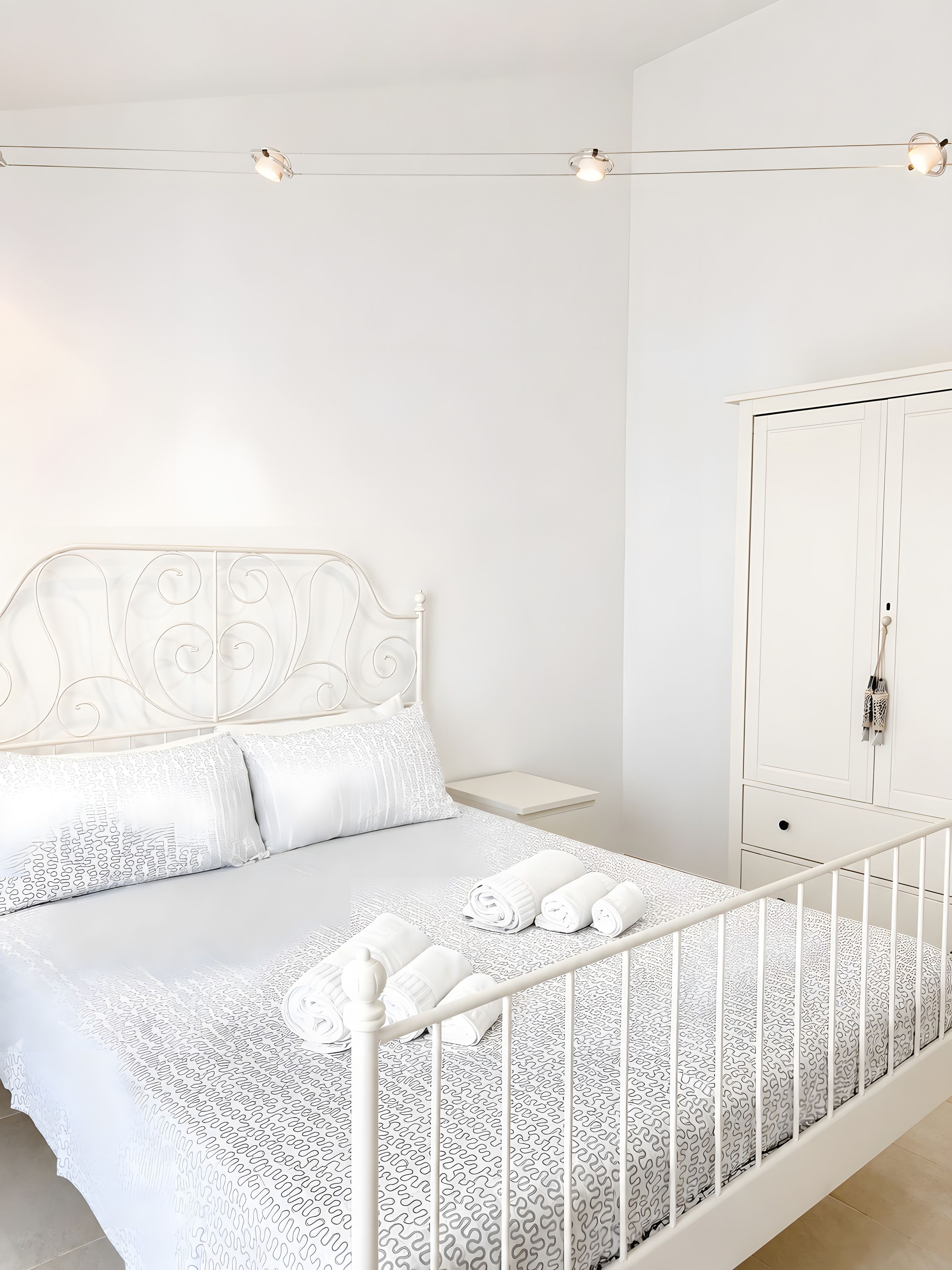 Een slaapkamer met een bed, een kledingkast en een nachtkastje.