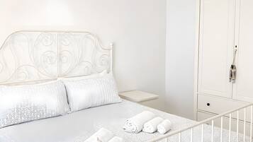 Een slaapkamer met een bed, een kledingkast en een nachtkastje.