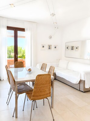 Ein modernes Zimmer mit Esstisch, Stühlen, einer Couch und einem großen Spiegel.