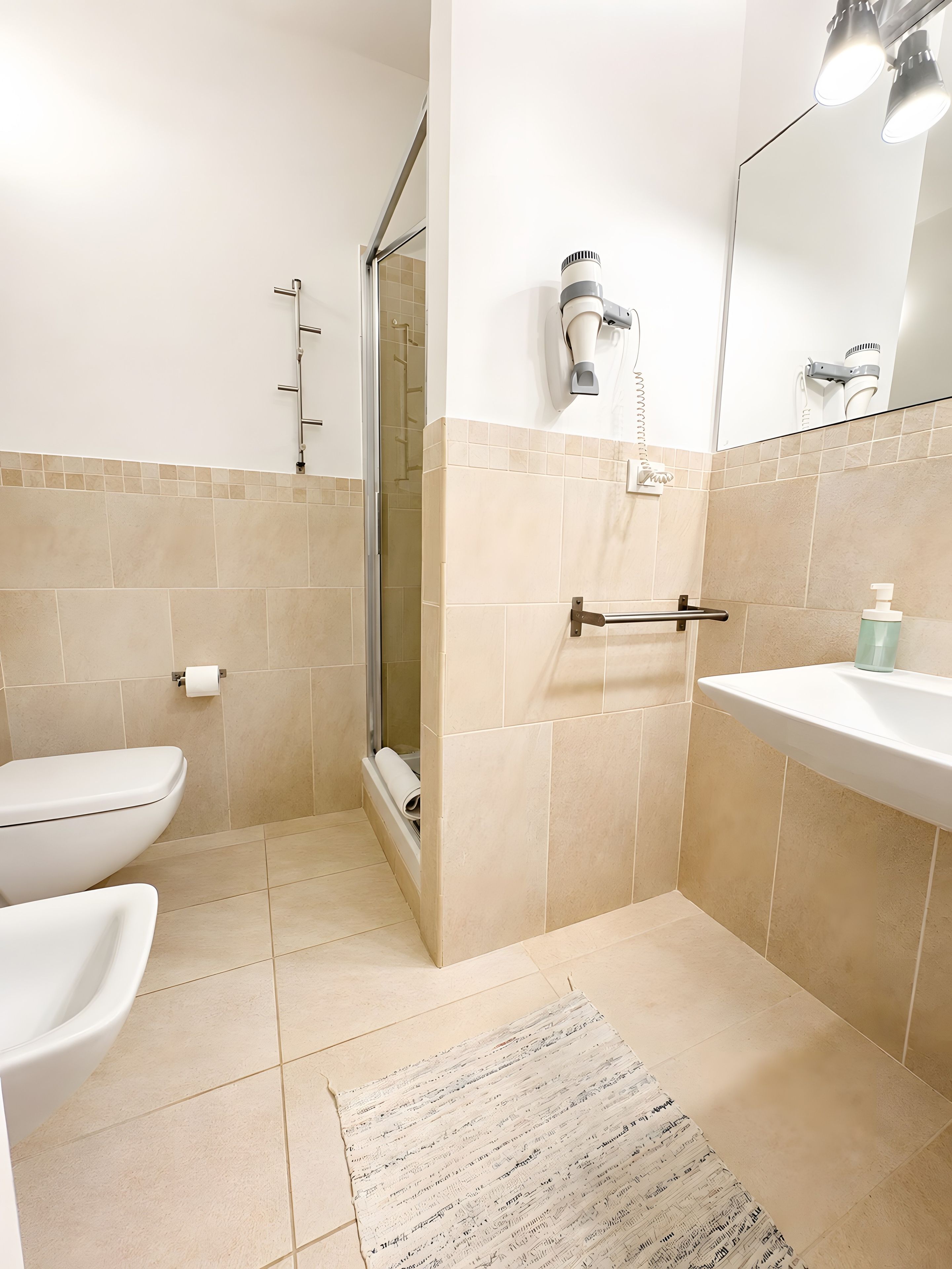 Un bagno con un water, un lavandino, una doccia e un porta asciugamani.
