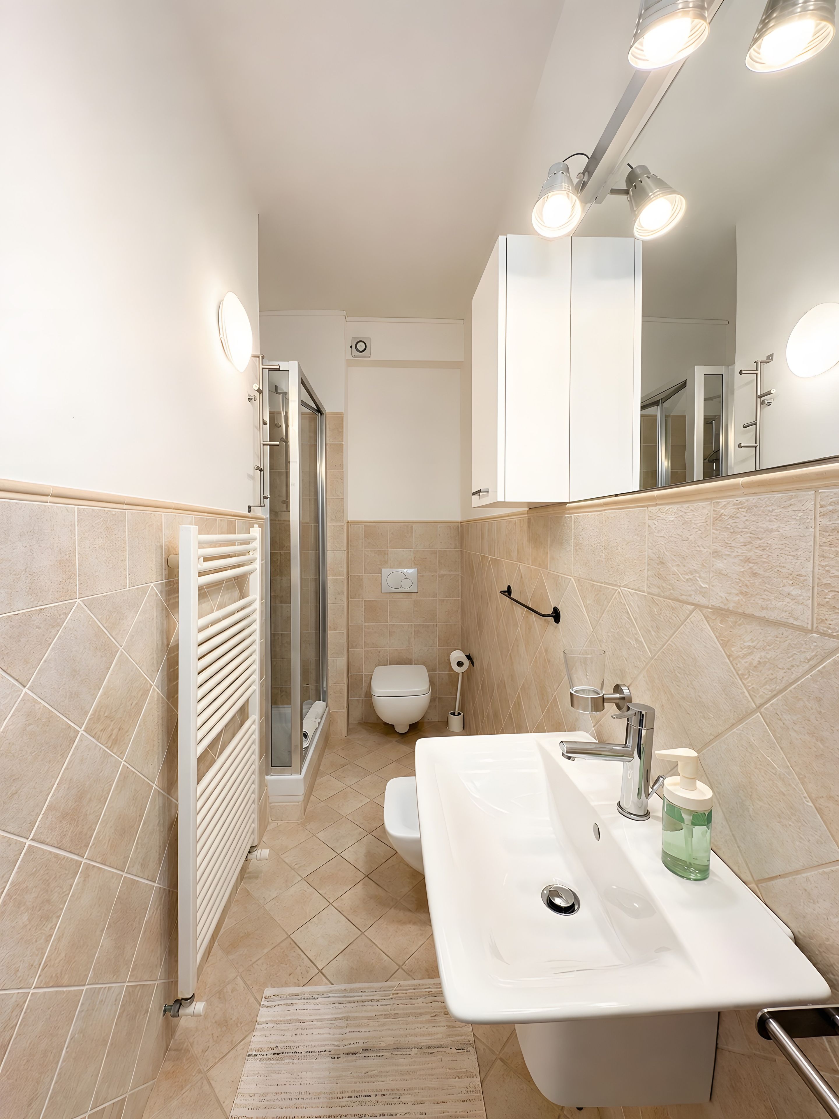 A modern bathroom with a white sink, mirror, and shower area.