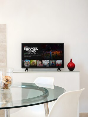 En platt-TV som är monterad på en vägg och visar Netflix-serien ”Stranger Things”.