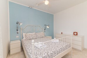 A bedroom with a bed, nightstands, a dresser, and a ceiling fan.