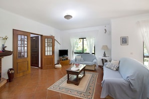 A living room with a sofa, a coffee table, a TV, and a door leading to another room.