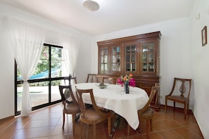 A dining room with a round table, chairs, a cabinet, and a window with curtains.