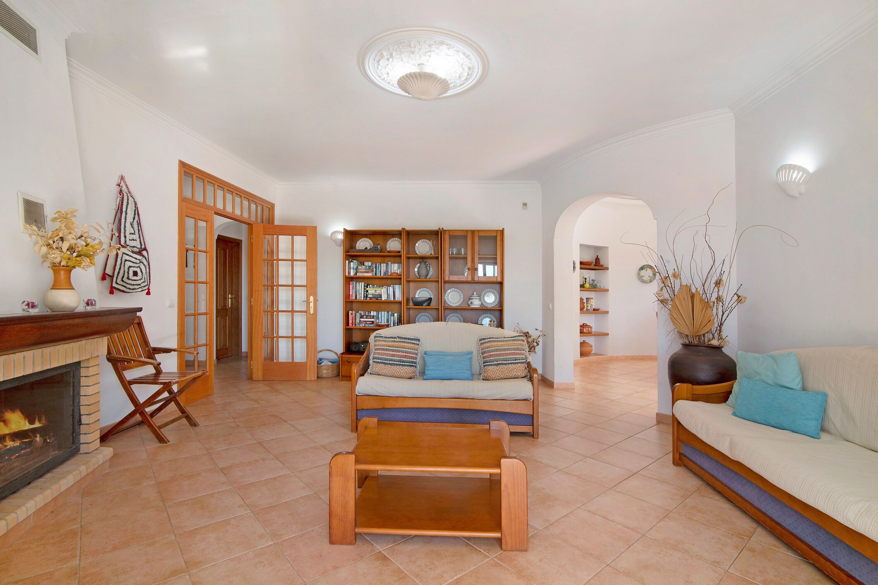 A living room with a fireplace, sofa, coffee table, bookshelf, and a dining area.