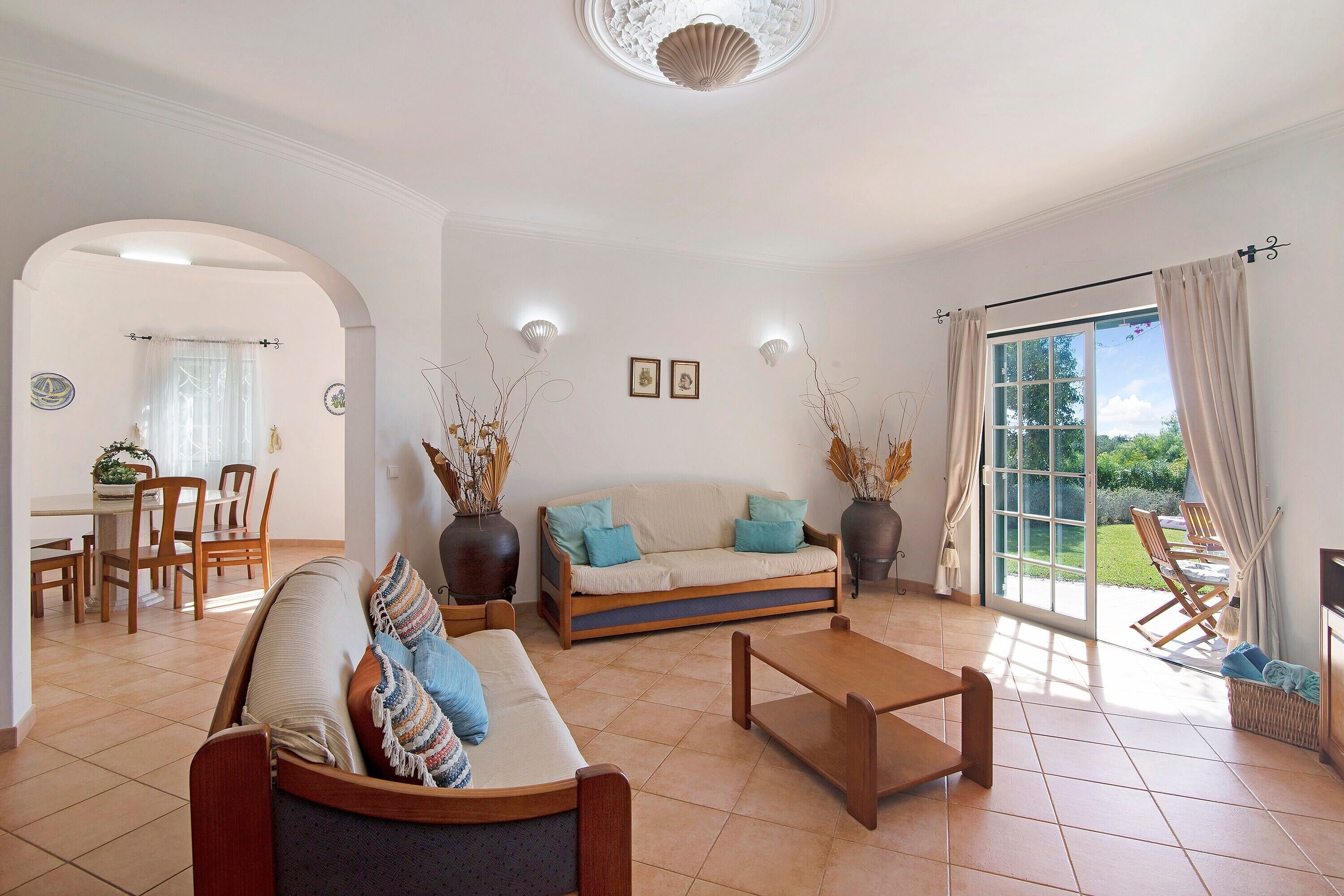 A living room with a sofa, coffee table, and dining area with chairs and a table.