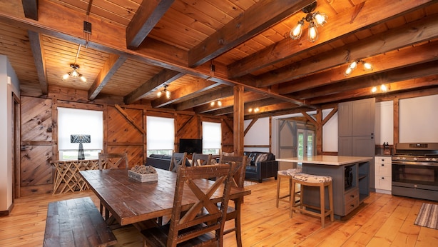 A spacious wooden dining area with a large table and chairs, a kitchen with modern appliances, and a cozy seating area with a sofa and a fireplace. - RIVER! Hot tub, Movie theater, Sauna, Massage chair (Conway)
