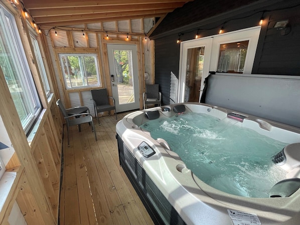 Un jacuzzi en una cabaña de madera con puerta de vidrio que da al exterior.