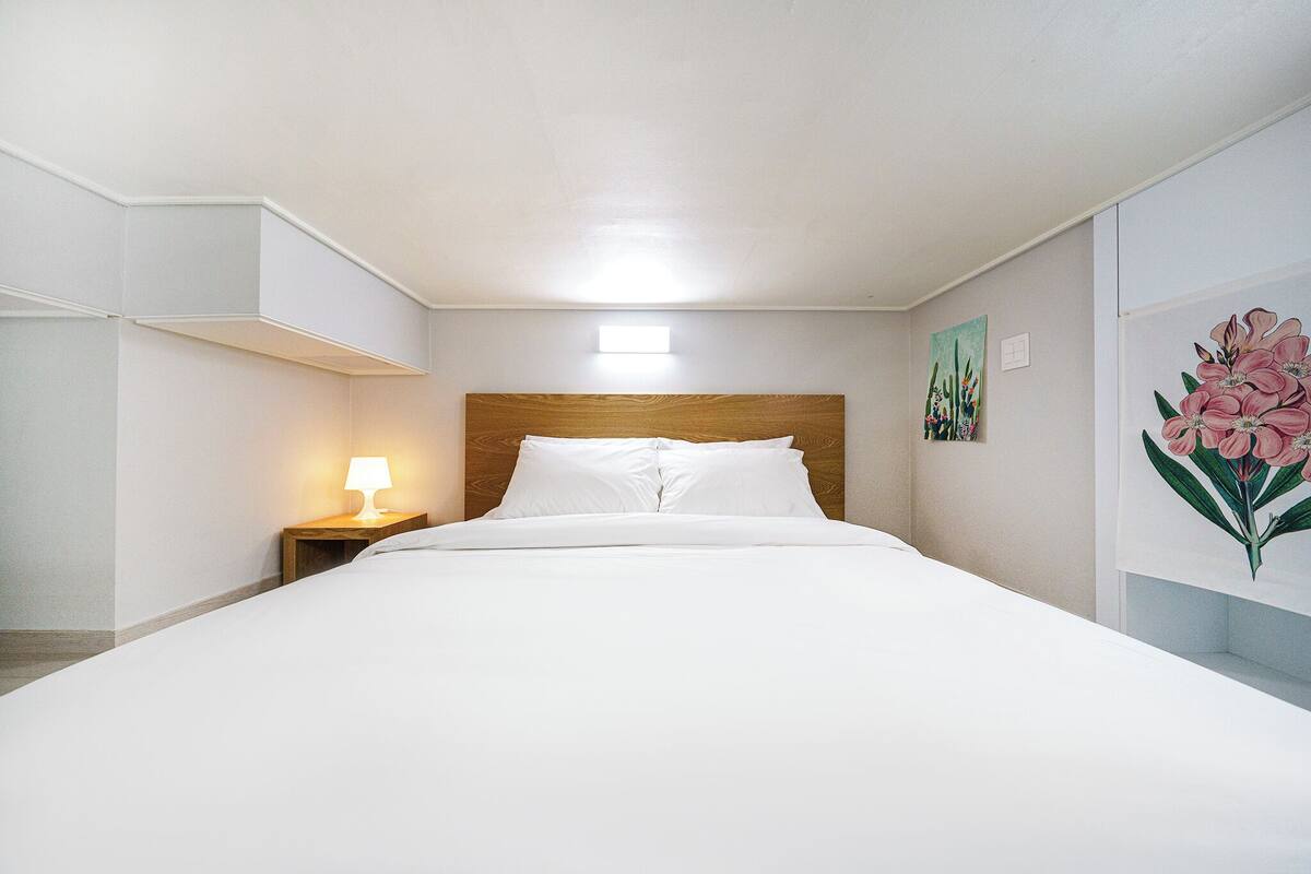 A neatly made bed with a wooden headboard, a bedside lamp, and a wall-mounted light fixture.