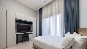 A modern hotel room with a large bed, a desk with a flat-screen TV, and a window with curtains. - Parkview Terrace Hotel (Paju)