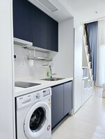 Una cocina moderna con lavadora integrada, un lavamanos y una escalera que conduce a un nivel superior.