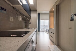 A modern kitchen with a built-in stove, a sink, and a window overlooking a balcony.