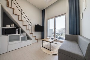 A modern living room with a staircase, a flat-screen TV, a coffee table, and a sofa.