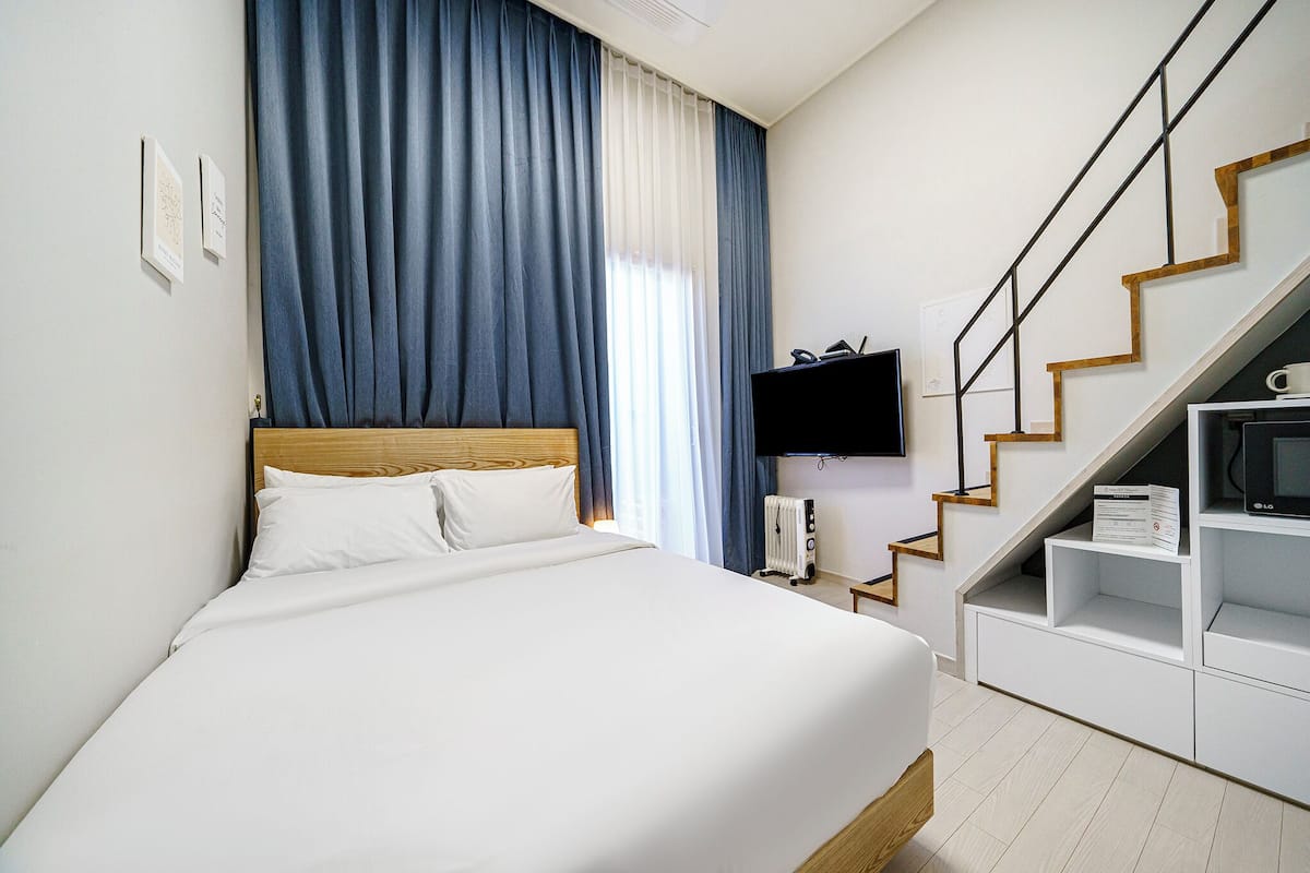 A hotel room with a bed, a TV, a heater, and a staircase.