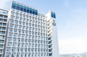 A modern hotel building with a prominent 'Parkview Terrace' sign, featuring a grid of balconies and a clear sky in the background.