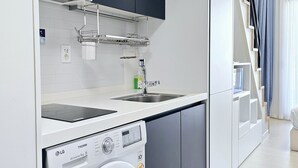 A modern kitchen with a built-in washing machine, a sink, and dark cabinets. - Parkview Terrace Hotel (Paju)