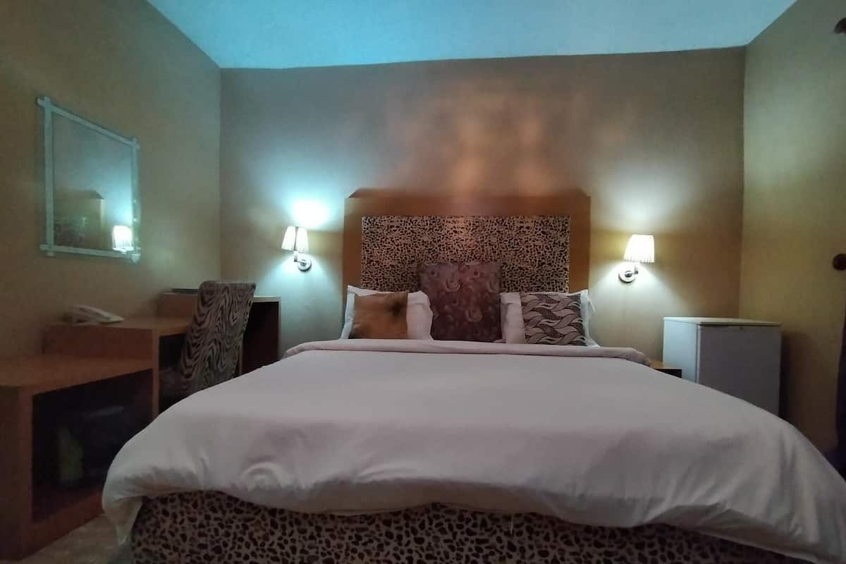 A hotel room with a bed, a desk, and a mirror.