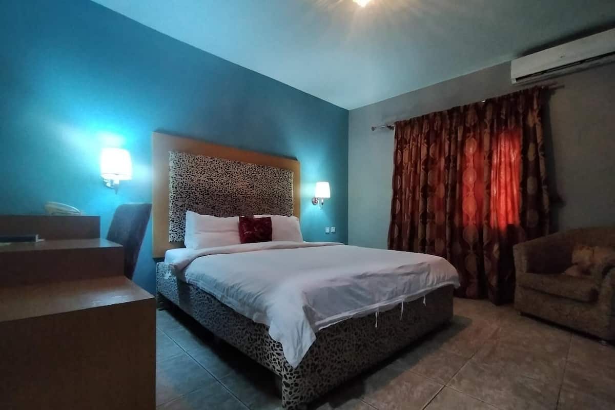 A bedroom with a bed, a desk, and a chair.