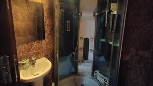 Ein Badezimmer mit Duschkabine, Waschbecken und Spiegel.