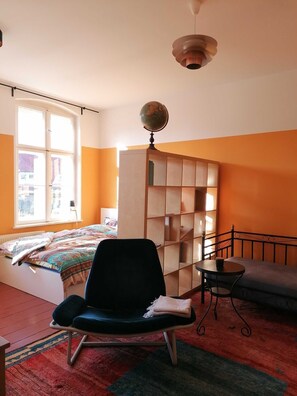 A bedroom with a bed, a chair, a small table, a globe, and a wardrobe.