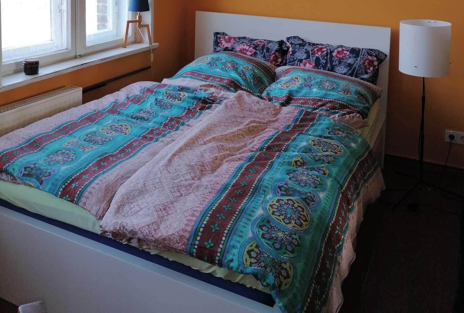 Un lit avec une literie à motifs, une lampe de chevet et une fenêtre donnant sur un beau paysage.