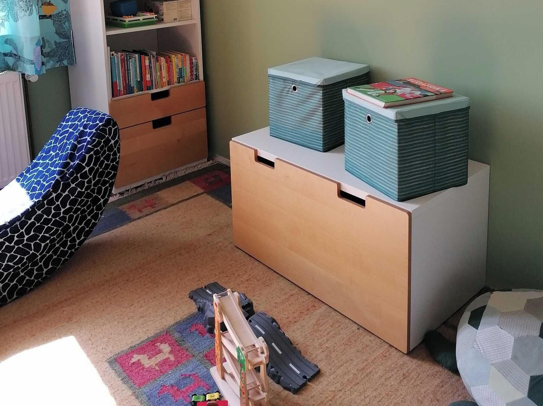 Ein Spielbereich für Kinder mit Bücherregal, Aufbewahrungsboxen und einer Modelleisenbahn.