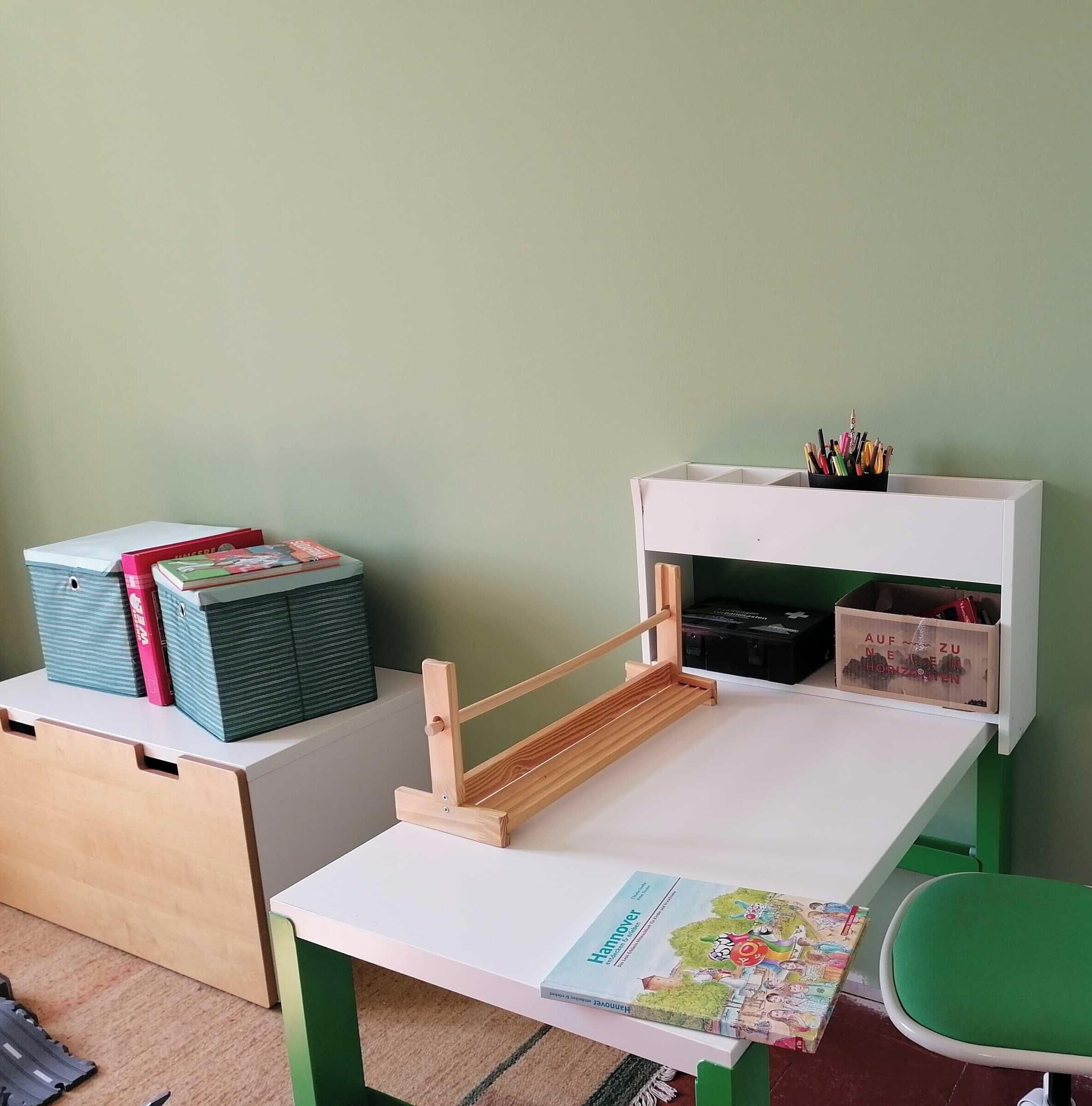 Escritorio infantil con un libro, un portalápices y cajas de almacenamiento.