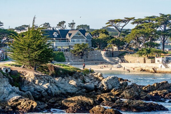 A coastal property with a large house, rocky shoreline, and a beach.