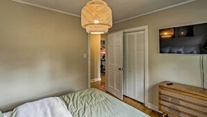 A bedroom with a bed, a wooden dresser, a television, and a door leading to another room. - Ideal Green Bay Home < 3 Mi to Lambeau Field! (Green Bay)