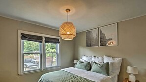 A bedroom with a bed, a window, a hanging light fixture, and a small table with a lamp. - Ideal Green Bay Home < 3 Mi to Lambeau Field! (Green Bay)