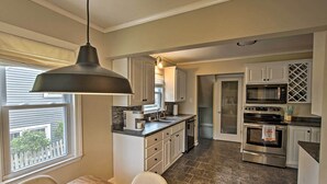 A modern kitchen with white cabinets, a stainless steel oven, and a dining area with a wooden table and chairs. - Ideal Green Bay Home < 3 Mi to Lambeau Field! (Green Bay)